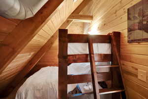 Bedroom with wooden walls, wooden ceiling, and vaulted ceiling