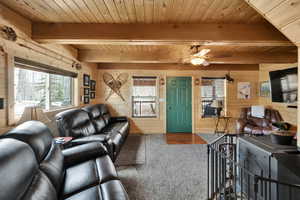Living area featuring carpet floors, wood walls, wooden ceiling, and a healthy amount of sunlight