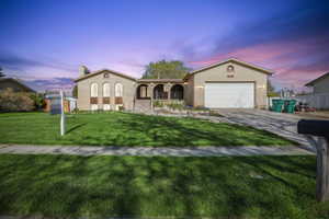 Mediterranean / Spanish house with an attached garage, a chimney, brick siding, a porch, and driveway
