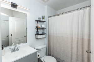 Full Guest Bathroom with toilet, a textured ceiling, and vanity
