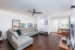 Living room with a ceiling fan and dark wood finished floors
