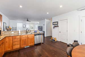 Kitchen with brown cabinets, stainless steel dishwasher, a sink, ceiling fan, and a peninsula