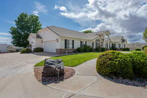 Ranch-style home with a tiled roof, a front yard, concrete driveway, an attached garage, and stucco siding