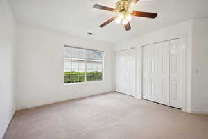 Unfurnished bedroom with visible vents, multiple closets, baseboards, and light carpet
