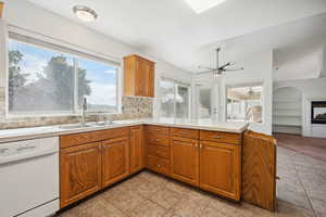 Kitchen with ceiling fan, a sink, dishwasher, light countertops, and a peninsula