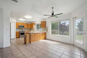 Kitchen with appliances with stainless steel finishes, light countertops, a peninsula, baseboards, and decorative backsplash