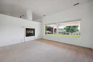 Unfurnished living room featuring visible vents, carpet flooring, a multi sided fireplace, and baseboards