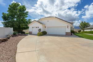 Ranch-style home featuring brick siding, an attached garage, driveway, and stucco siding