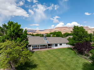 Rear view of house with a patio, a lawn, and a mountain view