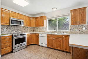 Kitchen with light countertops, a sink, backsplash, and stainless steel appliances