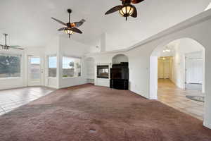Unfurnished living room featuring tile patterned floors, baseboards, a ceiling fan, and carpet floors