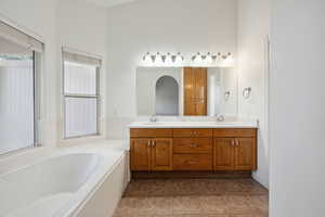 Full bathroom with double vanity, a sink, and a bath