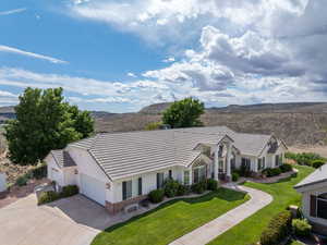 View of front facade with a front lawn, stucco siding, a mountain view, driveway, and a tile roof