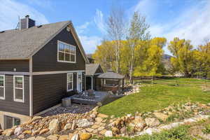 Exterior space with a lawn, fence, a shingled roof, a jacuzzi, and a gazebo