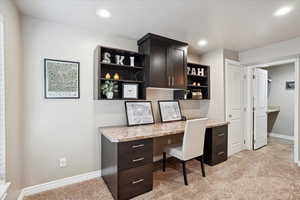 Unfurnished office featuring built in study area, recessed lighting, baseboards, and light colored carpet