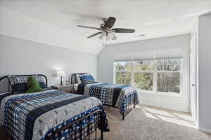 Carpeted bedroom with a ceiling fan, a textured ceiling, visible vents, baseboards, and lofted ceiling
