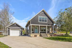 View of front of house featuring covered porch, driveway, a front lawn, and a garage