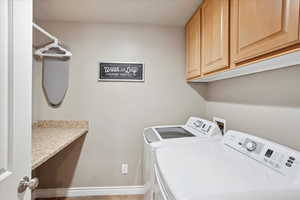 Laundry area featuring cabinet space, baseboards, and washing machine and dryer