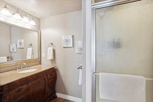 Full bath with vanity, a textured ceiling, tile patterned flooring, and a shower stall