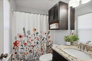 Full bathroom with toilet, a shower with shower curtain, and vanity