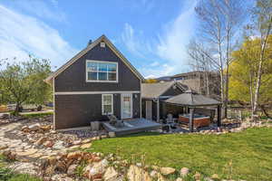 Back of property featuring fence, a yard, a wooden deck, and a hot tub