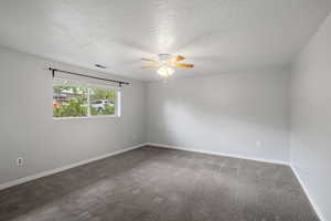 Empty room with carpet floors, a ceiling fan, a textured ceiling, and visible vents