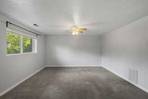 Carpeted empty room with visible vents, a ceiling fan, and a textured ceiling
