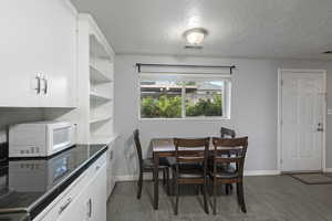 Dining area featuring a textured ceiling, baseboards, wood finished floors, and visible vents