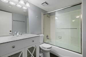 Bathroom with visible vents, tile patterned flooring, vanity, toilet, and combined bath / shower with glass door