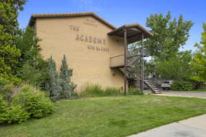 View of property exterior with stairs, brick siding, a deck, a tiled roof, and a yard