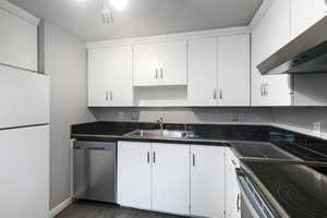 Kitchen featuring wall chimney range hood, a sink, electric range oven, freestanding refrigerator, and stainless steel dishwasher