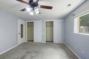 Unfurnished bedroom featuring two closets, a textured ceiling, visible vents, and carpet floors
