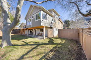Rear view of house with a fenced backyard, stairs, a lawn, and a patio area