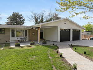Ranch-style house featuring fence, a front lawn, brick siding, a chimney, and driveway