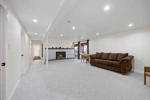 Living room with baseboards, light carpet, a brick fireplace, and recessed lighting