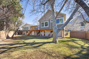 Rear view of property with a lawn, a fenced backyard, a wooden deck, and stairway,  separate basement entrance
