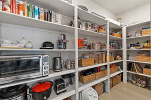 Walk-in pantry featuring floor-to-ceiling shelving and light hardwood flooring
