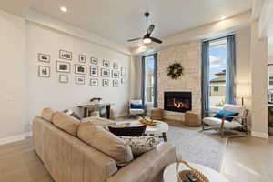 Living area featuring ceiling fan, recessed lighting, a stone fireplace, light hardwood floors, and plenty of natural light