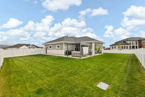 Back of house featuring a shingled roof, a patio area, an outdoor living space, a yard, and a fenced backyard