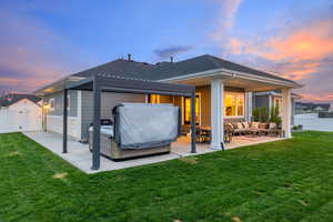 Rear view of property with a lawn, outdoor living area, a covered patio, hot tub with pergola, and a fenced backyard