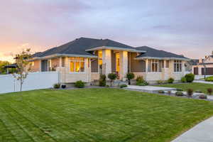 Prairie-style house with a professionally landscaped front yard, covered porch, exterior lighting, mixed finishes of cement-fiber siding and light colored stone, with vinyl fence