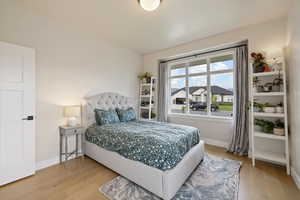 Spare bedroom featuring light hardwood floors, large windows, and two-tone paint