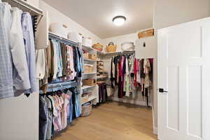 Spacious walk-in closet with light hardwood floors