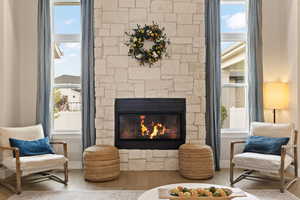 Living area featuring hardwood floors and a fireplace with stone surround