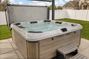 View of patio featuring fence and a hot tub