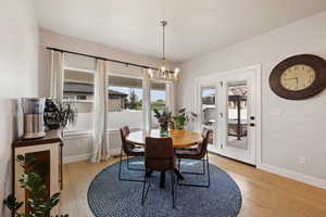 Dining space featuring light hardwood floors, large windows, notable chandelier, and patio door