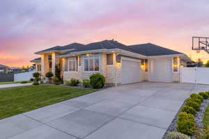 Prairie-style home featuring a yard, driveway, fence with gate, and exterior lighting