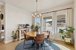 Dining space featuring light hardwood floors, large windows, and notable chandelier