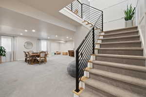 Carpeted stairs with horizontal metal railing, large open floorplan living space