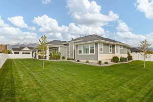 Rear view of property with a lawn, stone siding, central AC, and a fenced backyard